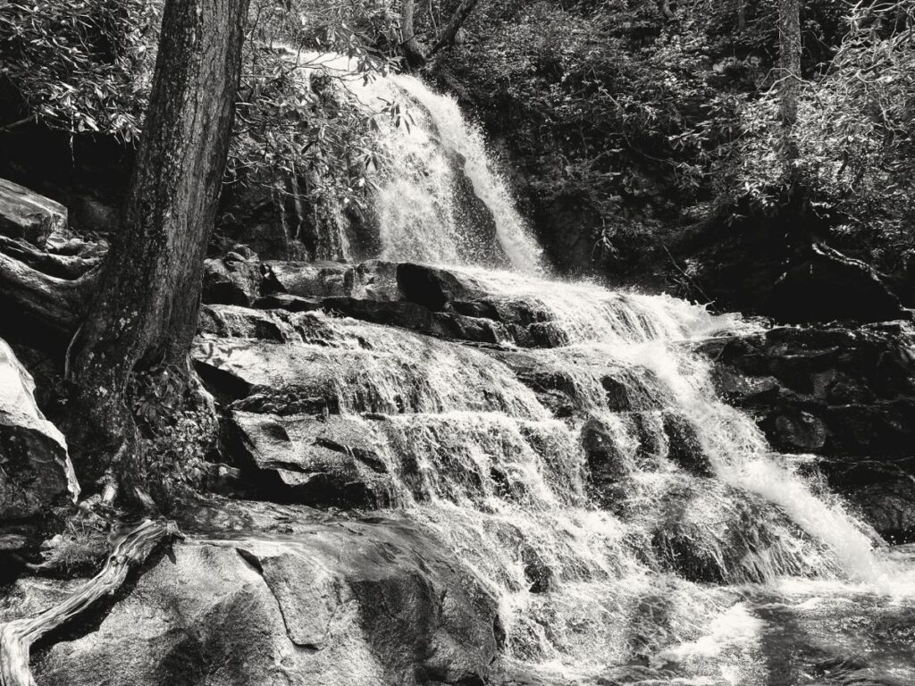 Waterfall falling down many layers of rock. Picture is black and white of Laurel Falls, one of the easy waterfalls in Great Smoky Mountains National Park to get to with kids