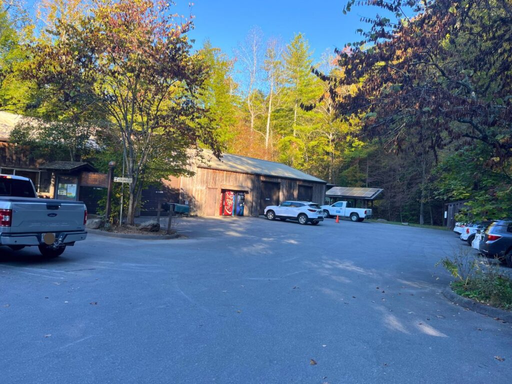 Visitor Center at Tremont in Great Smoky Mountain National Park. A wooden one story building with a red coca cola vending machine outside. A few cars are parked around the area