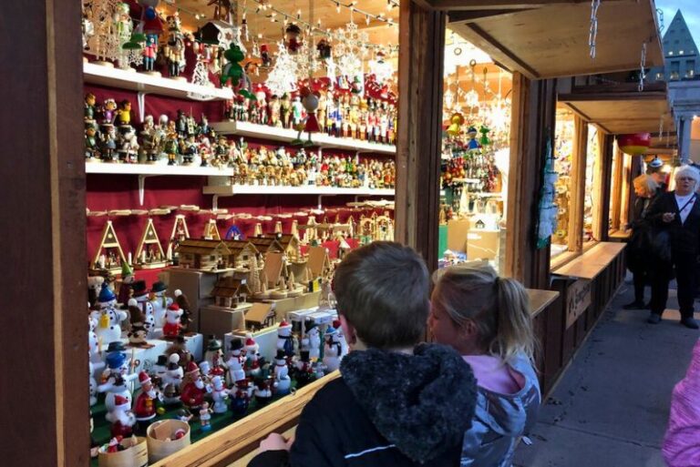 two kids looking at christmas ornaments at a Christkindlmarket in Denver. The angle is looking closely down the wooden booths
