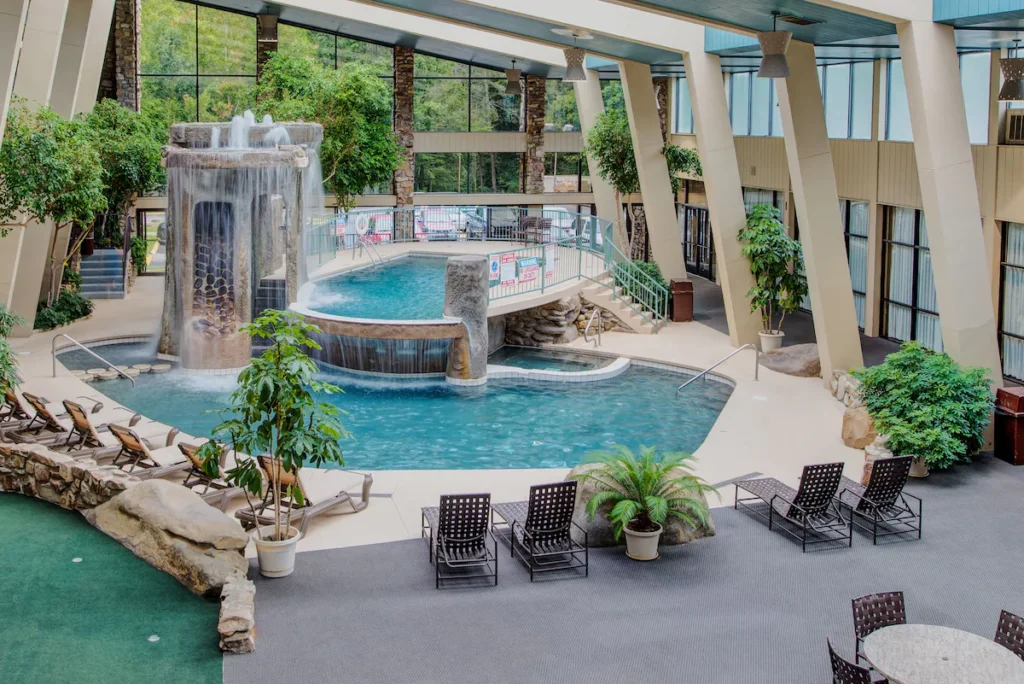 large indoor pool in an atrium of a hotel.  Two pools next to each other with a tall waterfall fountain behind the first one.  Tall ceilings