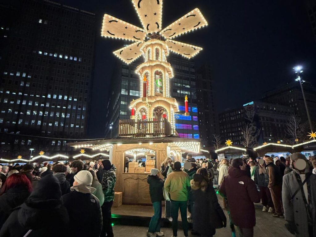 A Christmas Pyramid wiht wooden-like blades on top lit up in the night in Philadelphia at the Christkindl Market