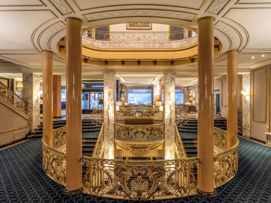 a palace-like set of stairs and foyer with dark carpet