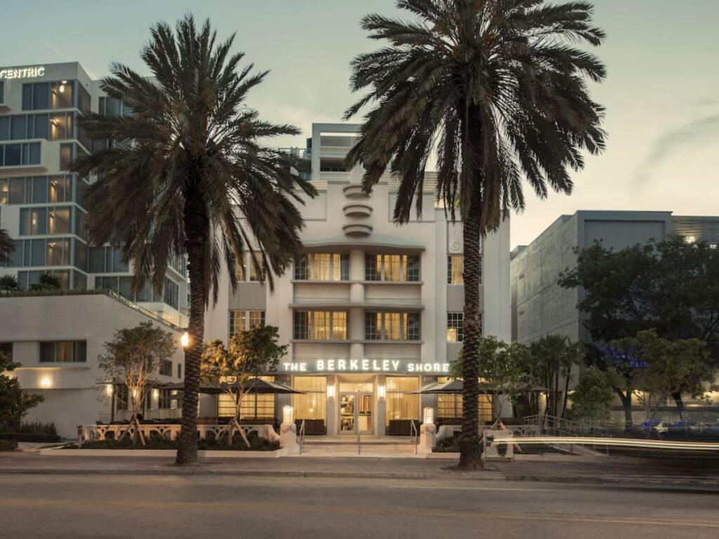 looking at a modern beach hotel.  White building with road in front, two large palm trees